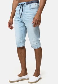 Shorts de denim azul claro con cinturilla elástica, detalle de cordón y dobladillo vuelto. Presenta bolsillos delanteros y traseros para mayor funcionalidad.