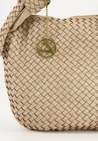 Geweven beige leren tas met een geknoopte handgreep en een gouden ronde tag met de tekst "Venezia." Heeft een gestructureerd, verstrengeld ontwerp.