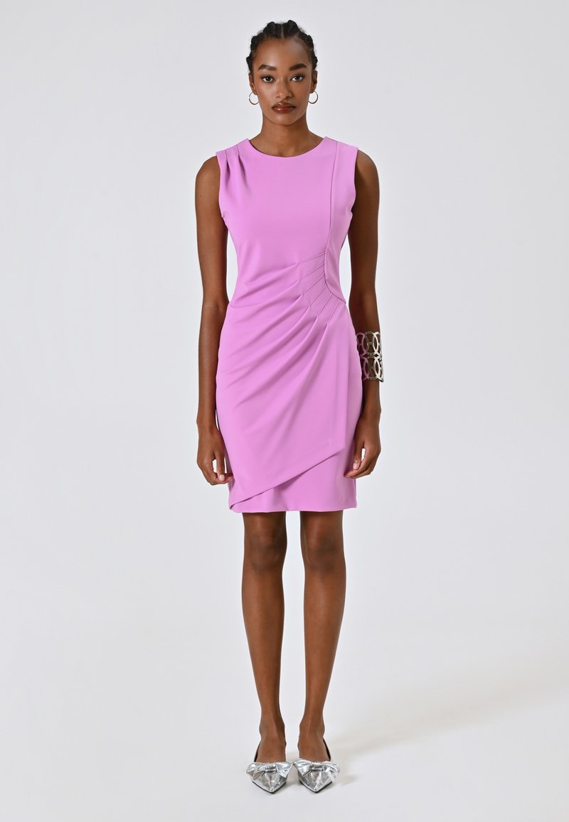 Fuchsia ärmelloses Kleid mit drapiertem Design und vorderen Falten. Das Model trägt silberne flache Schuhe mit Schleifendetail und ein Metallarmband.