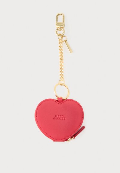 Κόκκινη δερμάτινη θήκη νομισμάτων σε σχήμα καρδιάς με χρυσή αλυσίδα και κλιπ, ανάγλυφο λογότυπο "Marc Jacobs" και μικρή λεπτομέρεια φερμουάρ.
