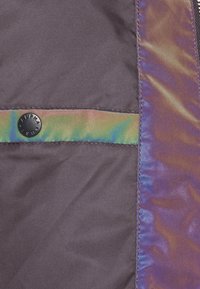 Fioletowa tkanina z subtelnym połyskiem, z szerokim irydyzującym paskiem i czarnym zatrzaskiem oznaczonym "ALPHA". Gładka struktura całości.