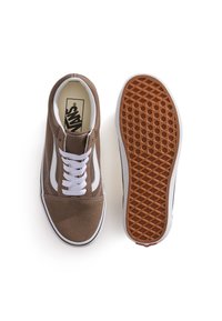 Un par de zapatillas Vans marrones con cordones blancos y una franja lateral, mostrando la vista superior del zapato izquierdo y la suela del zapato derecho.