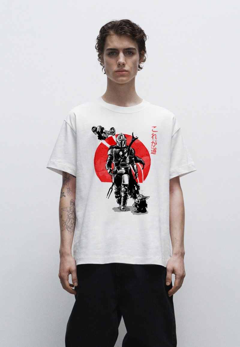 Bílý bavlněný tričko s černým a červeným grafickým potiskem postavy a malé postavičky, s japonským textem na přední straně.
