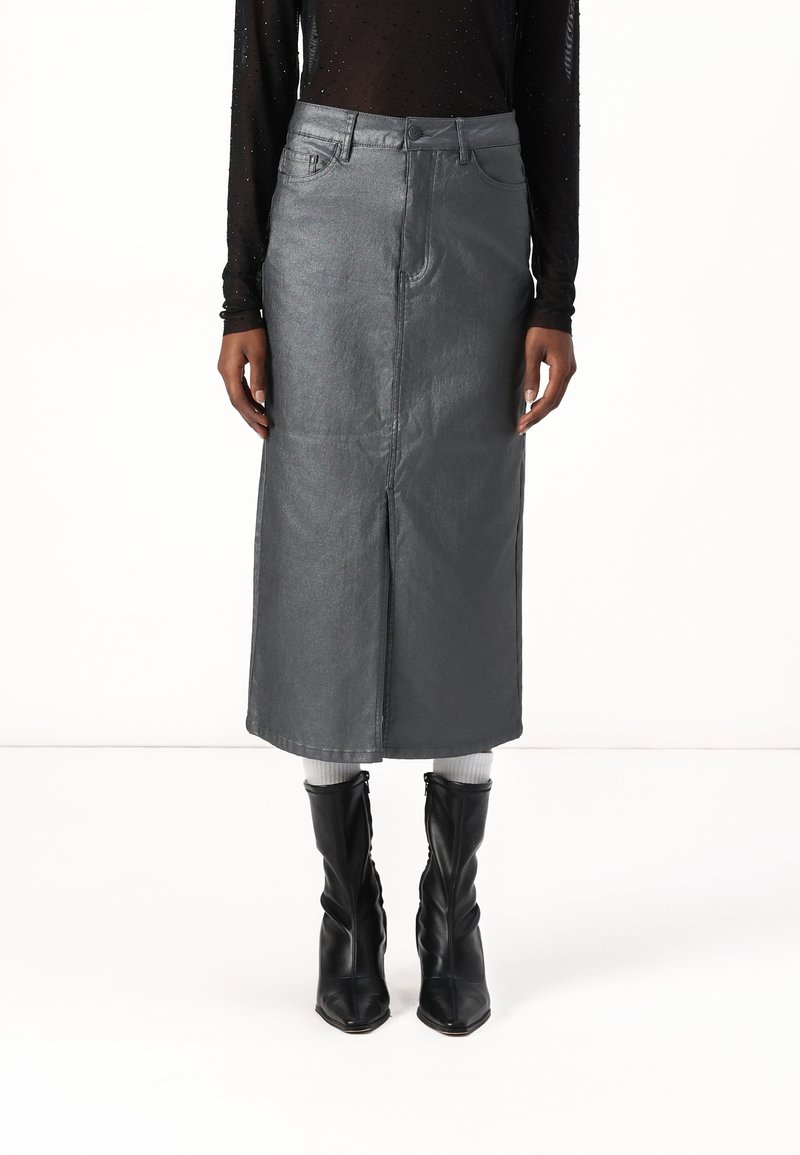 Jupe midi en denim gris avec fente avant, cinq poches et passants de ceinture. Associée à des bottines noires et un haut noir à manches longues texturé.