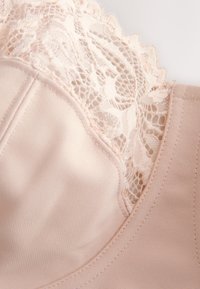 Sutien roz deschis, realizat dintr-un material neted cu detalii delicate din dantelă pe marginea superioară, prezentând un model floral și o textură moale.