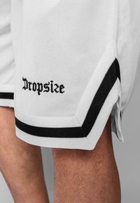 Bijele mrežaste atletske kratke hlače s crnim detaljima, sa obrubljenim rubom i izvezenim "Dropsize" logotipom na lijevoj nozi.
