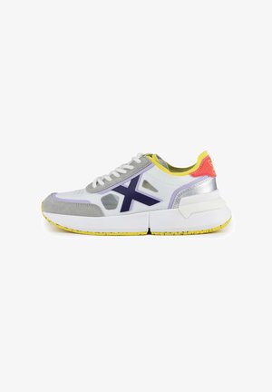 Sport sneakers i hvid, grå og lilla. Har en struktureret overdel, gule detaljer og en tyk hvid sål med et spottet design.
