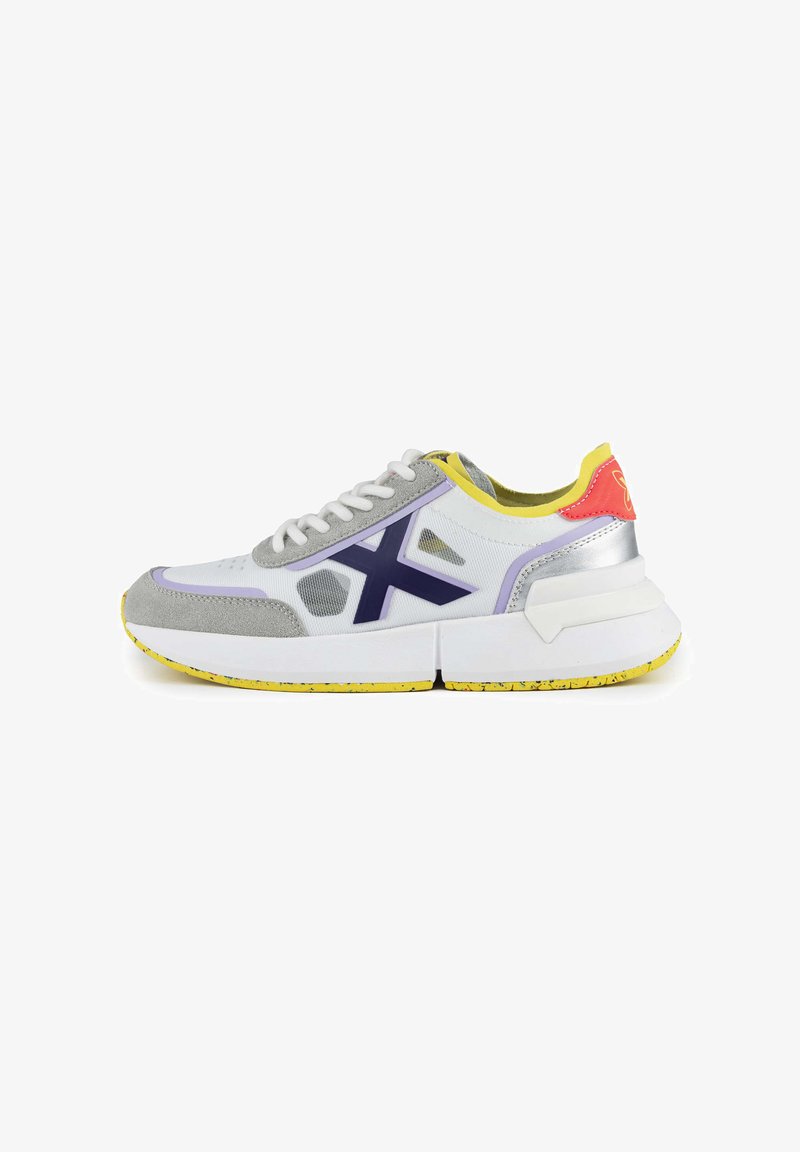 Sportliche Sneakers in Weiß, Grau und Lila. Sie verfügen über ein strukturiertes Obermaterial, gelbe Akzente und eine dicke weiße Sohle mit einem gesprenkelten Design.