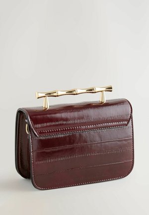 Bordó lakkbőr borítéktáska merev formával, arany színű bambusz stílusú fogantyúval és vízszintes texturált részletekkel.