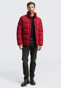 Crvena podstavljene jakne s visokim ovratnikom, s horizontalno kvadratnim pređama i zatvorenim džepom na prsima. U kombinaciji s crnim farmerkama i čizmama.