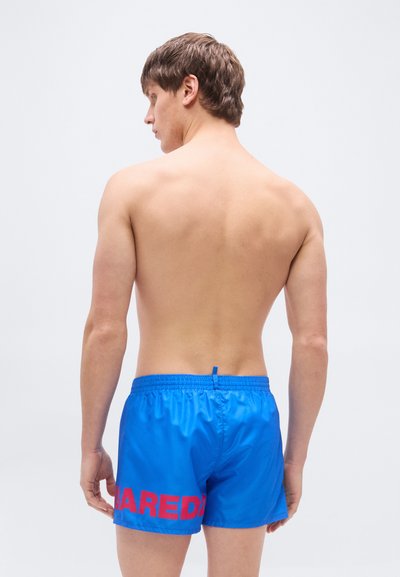 Μπλε μαγιό σορτς από ελαφρύ υλικό με μέση που δένει με κορδόνι, με έντονα κόκκινα γράμματα στην αριστερή πλευρά.