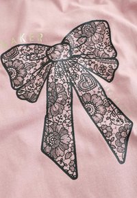 Tessuto rosa con un grande design di fiocco in pizzo nero e motivi floreali, accentuato dal nome del marchio "Baker" in lettere dorate.