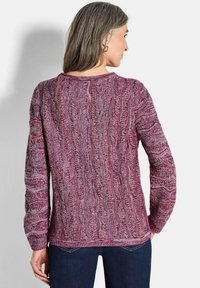 Texturiertes Strickoberteil in Schattierungen von Rosa und Lila, mit einem wellenförmigen Muster, langen Ärmeln und einem Rundhalsausschnitt.