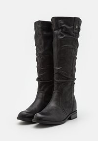 Botas negras hasta la rodilla hechas de cuero suave, con un diseño holgado, punta redondeada y un tacón bajo. Sencillos acentos en la parte superior.