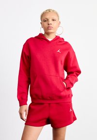 Rød bomull hettegenser med kengurulomme, ribbede mansjetter og hvit logodetalj. Kombinert med matchende røde shorts, som også har logo.
