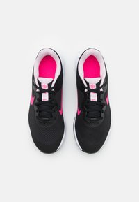 Zapatillas deportivas negras con acentos en rosa, parte superior de malla, cuello acolchado, suela blanca y cordones negros. Presenta el logo de Nike en los lados.