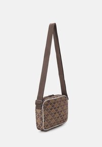 Brązowa torebka na ramię w geometryczne wzory liści. Posiada zamek błyskawiczny i materiałowy pasek. Akcentowana białymi lamówkami.