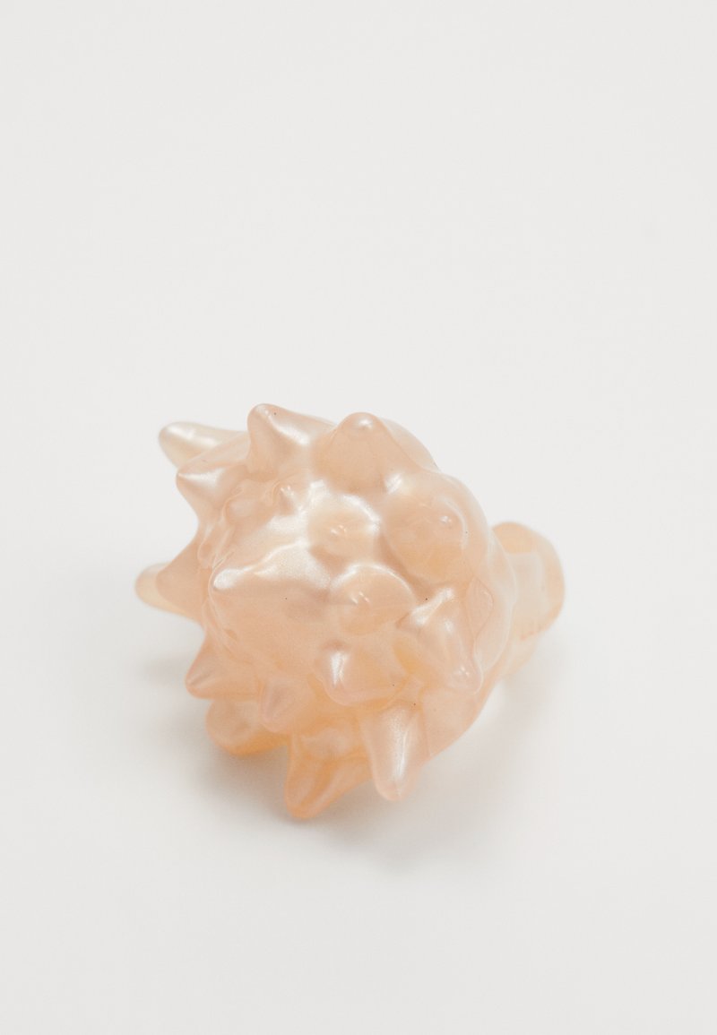 Polnate, breskvaste prstan z teksturirano, bodičasto zasnovo in sijajnim finishom. Narejen iz gladkega sintetičnega materiala.