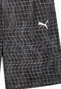 Čierne športové kra�ťasy s vlnkovaným mriežkovým vzorom, vyrobené z ľahkého materiálu. Na boku je malé biele logo Puma.