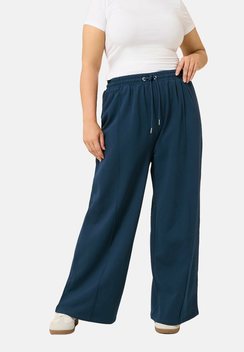 Navy vida byxa med breda ben, tillverkad av mjukt tyg med elastisk midja och dragsnöre. Har en avslappnad passform och sidofickor.