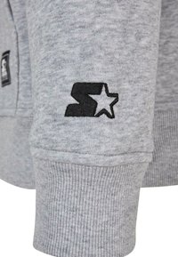 Hanorac gri cu manșete cu model în relief și un logo negru brodat cu un design de stea pe mânecă. Material moale, texturat.