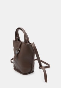 Piccola borsa in pelle marrone con una fibbia metallica arrotondata e una tracolla regolabile su uno sfondo bianco.