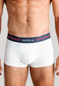 Vita bomullsboxershorts med en marinblå elastisk midjeband som har röda och vita ränder samt varumärket "ombre" tryckt på sig.