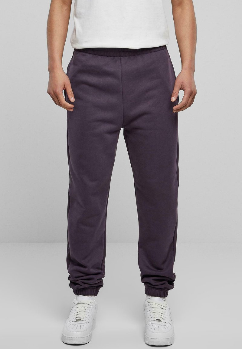 Lila sweatpants i en bomullsblandning, med resårmidja och avsmalnande anklar, kombinerade med vita sneakers.