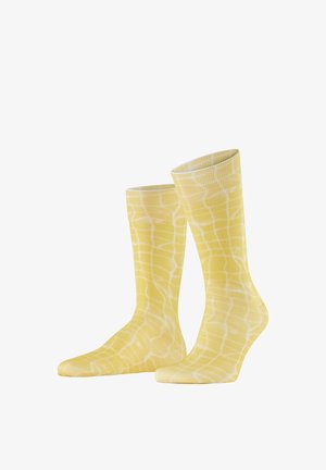 Chaussettes basses jaunes avec un motif de grille blanche irrégulière, présentées debout sur un fond blanc.