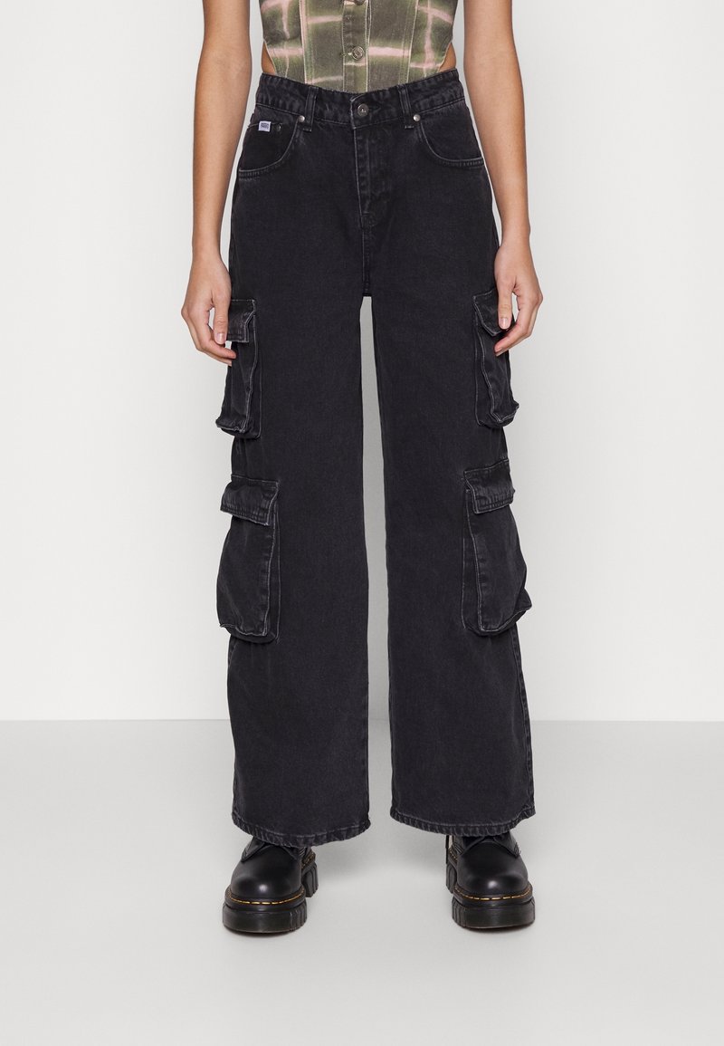 Svarta cargobyxor med lös passform, som har flera sidofickor, hög midja och kontrasterande sömmar. Tillverkade av denimstoff.