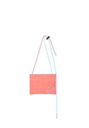 Korallenfarbene rechteckige Tasche mit weißem Smiley-Gesicht und dem Schriftzug „Petit“, befestigt an langen rosa und blauen Kordelriemen mit schwarzem Clip.