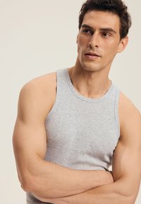 Szary bawełniany top na ramiączkach z okrągłym dekoltem i bez rękawów, charakteryzujący się dopasowanym krojem i gładką fakturą.