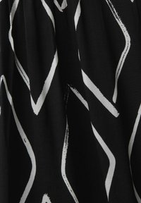 Tissu noir avec des lignes blanches en zigzag audacieuses et irrégulières créant un motif abstrait et dynamique.