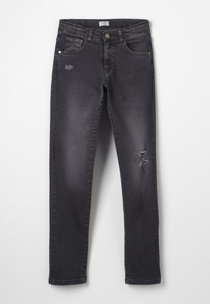 Vaqueros pitillo negros con ligeros desgastes en la parte superior del muslo y la rodilla, con bolsillos delanteros y traseros y trabillas para cinturón.