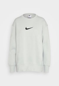 Ljusgrå Nike sweatshirt med rund halsringning, långa ärmar och en svart swoosh-logotyp på bröstet. Mjuk tyg med ribbad mudd och nederkant.