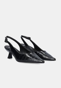 Zapatos de tacón negro tipo slingback elaborados en cuero texturizado con relieve de cocodrilo, con punta afilada y un tacón medio grueso para mayor estabilidad.