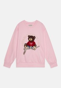 Sudadera rosa con cuello redondo, mangas largas y puños elásticos. Presenta un oso bordado y el texto "Establecido en 1981".