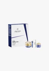 Zestaw pielęgnacyjny Shiseido Vital Perfection w niebiesko-białym opakowaniu zawiera dużą słoiczek, dwa mniejsze słoiczki oraz niebieski aplikator.