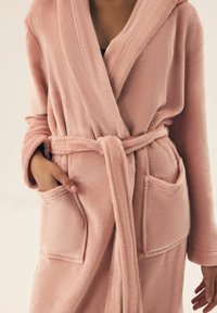 Różowy szlafrok z polaru z kołnierzem typu szal, zawiązywany paskiem, z dwiema przednimi kieszeniami i miękkim, teksturowanym wykończeniem.
