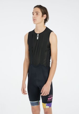 Zwarte fietsbroek met een fitted mouwloos bovenstuk, gemaakt van mesh materiaal en gekleurde prachtaccenten op de broeken. Tekst op de voorkant.