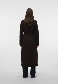 Lungo cappotto marrone con vita cinturata, realizzato in un materiale morbido. Il cappotto ha una linea dritta e maniche lunghe.