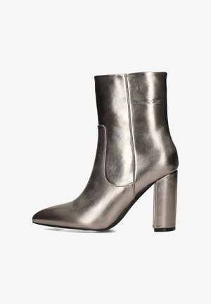 Bottine grise métallisée avec un bout pointu, un haut talon carré et un design de panneaux latéraux. Texture lisse et silhouette épurée.