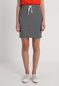 Randig svart och vit kjol med resårmidja och vit dragsko, med framfickor och en åtsittande design.