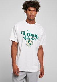 Fehér, oversized szabású pamut póló, a mellkason elhelyezett zöld "Urban Classics" márkalogóval és földgömb grafikával.