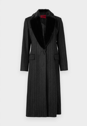 Black pinstriped coat made of structured fabric, featuring a faux fur collar, two front pockets, and a single-button closure.