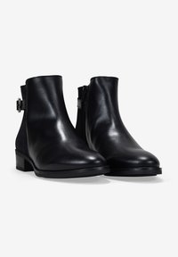 Botas de tobillo de cuero negro con un acabado suave, puntera redondeada y un tacón bajo en bloque. Presentan un cierre lateral con cremallera y un detalle de correa con hebilla.