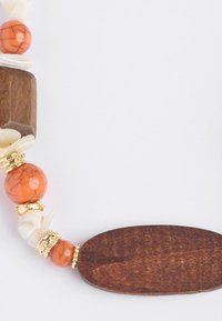 Houten ketting met oranje crackle kralen, witte schelpelementen en vergulde hardware. Ovale houten centerpiece met een gladde textuur.
