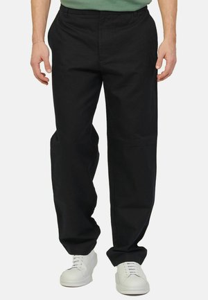 Pantaloni neri, dalla vestibilità rilassata, realizzati in cotone. Presentano una texture liscia, tasche laterali e una vita dal design minimalista. Abbinati a sneakers bianche.
