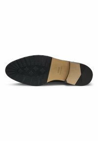 Suola in gomma nera con un pattern di grip testurizzato, forma curvata nella parte anteriore e un inserto beige a contrasto vicino al tallone.