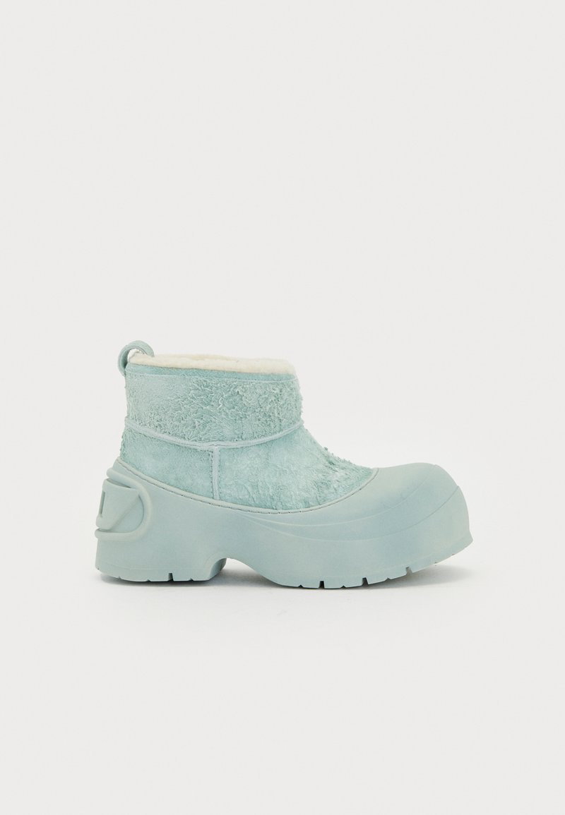 Helleblaue Winterstiefel mit einer massiven Gummisohle und Schafsleder-Futter, ausgestattet mit einer strukturierten Oberseite und einer Zuglasche auf der Rückseite.